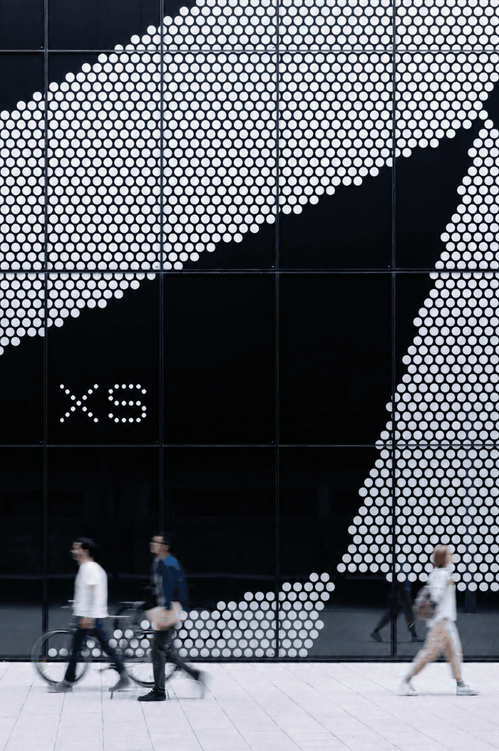 People passing an architectural XS facade